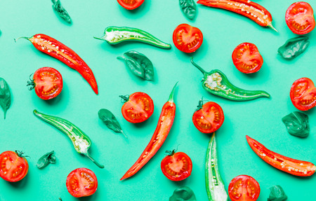 Above view at cutted chili pepper and basil with tomatoes on green backgroundの写真素材