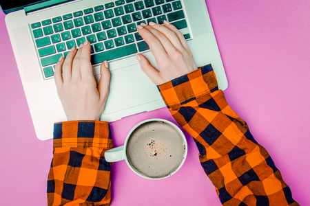 Businesswoman hands with laptop and cup of coffee on purple background. Above viewの写真素材