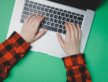 Freelancer woman hands typing on laptop at green backgroundの写真素材