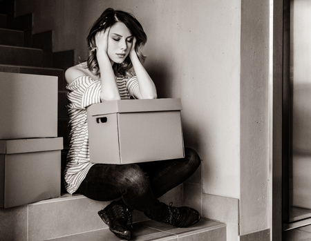 young woman with moving boxes sitting on stairs in house. . Image in black and white color styleの写真素材
