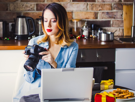 Beautiful young photographer have a coffee break while sitting working with camera and laptop. Concept of work with startup business in Holiday timeの写真素材
