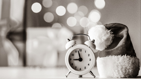 Vintage Alarm clock in Santa Claus hat with Christmas gift and Ligths on backgroundの写真素材