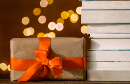 Christmas gift box and pile of books with fairy lights on backgroundの写真素材
