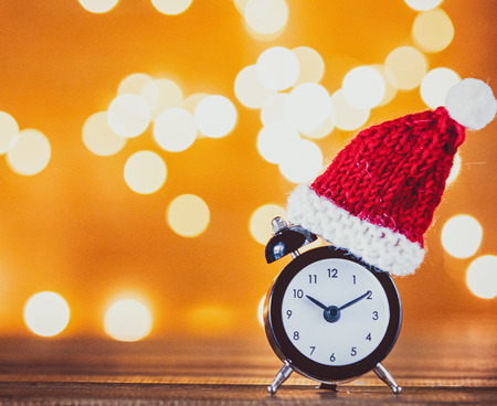 Vintage alarm clock with Santa Claus hat and Fairy Lights on backgroundの写真素材