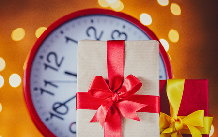 Christmas gifts and vintage alarm clock with Fairy Lights on backgroundの写真素材