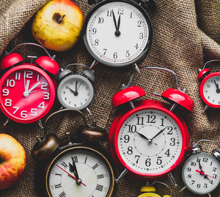Apples and alarm clocks on jute sack background. Autumn season harvestの写真素材