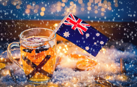 Cup of tea and flag of Australia on snow and fairy lights background. Christmas time decorationの写真素材