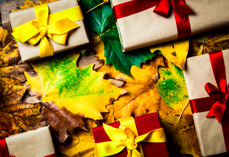 Gift boxes on maple leaves on wooden background. Above viewの写真素材