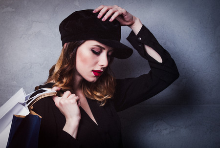 Style redhead girl in hat with shopping bags on grey backgroundの写真素材