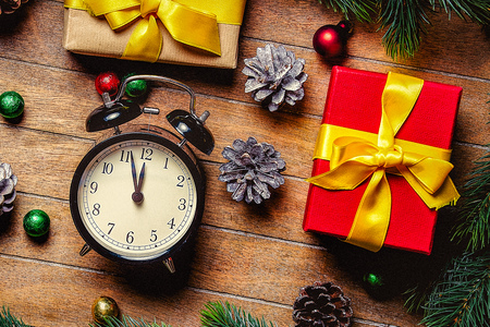 Christmas gift boxes and little alarm clock near pine branch on wooden table. Hight angle point of...