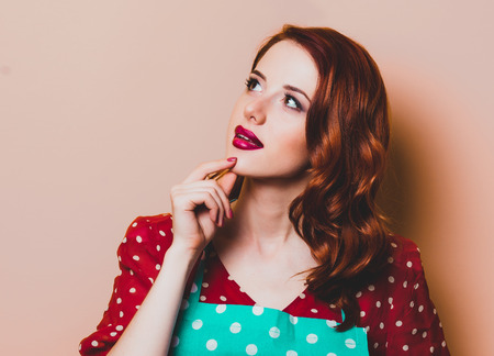 Young redhead housewife with gloves on yellow backgroundの写真素材