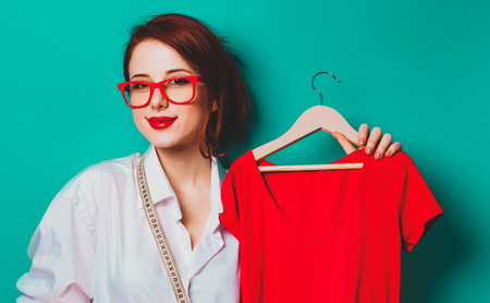 Young redhead businesswoman as startup tailor with clothes on blue backgroundの写真素材