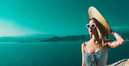 Young redhead girl in hat and dress with sea coastline on Balos, Crete, Greece