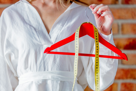 Fashion designer hands with hanger and measure tape. Side view. No faceの写真素材