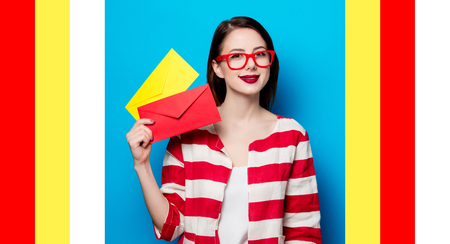 portrait of beautiful young smiling woman with two envelopes on blue background