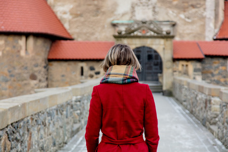 Beautiful woman in red coat stay near castle in winter time. Polandの写真素材