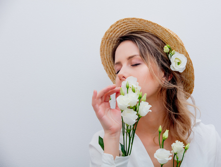 Beautiful woman with white roses in sleeves in hat on white background. Springtime concept or Valentines Day holidayの写真素材