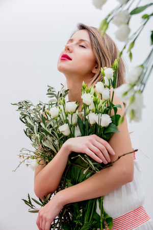 Beautiful woman with white roses bouquet dressing in a white dress. Springtime concept or Valentines Day holidayの写真素材