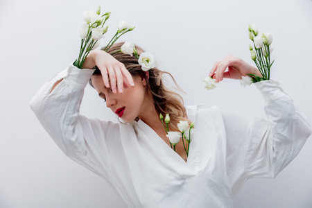 Beautiful woman with white roses in sleeve, dressing in a white dress. Springtime concept or Valentines Day holidayの写真素材