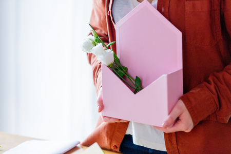 Female holding a pink envelope with white roses. Florist conceptの写真素材