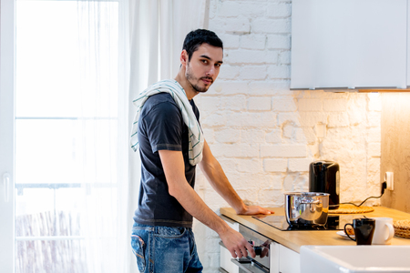 Young man in black shirt cooking at kitchen in home. candid viewの写真素材