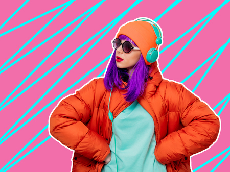 Portrait of a beautiful girl with purple hair in orange hat and jacket and with headphones on white background. Trendy styleの写真素材