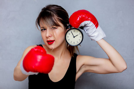 Young woman in boxing gloves with alarm clock on gray background. 90s flashlight styleの写真素材