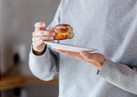 Man eating donut on breakfast at kitchen at home.の写真素材