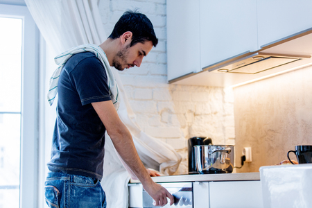 Young man in black shirt cooking at kitchen in home. candid viewの写真素材