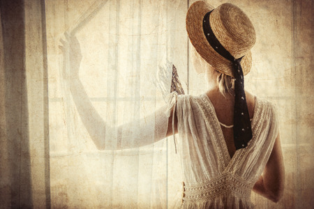 Woman in white dress holding lavender in hands and stay near window. Image in high key styleの写真素材