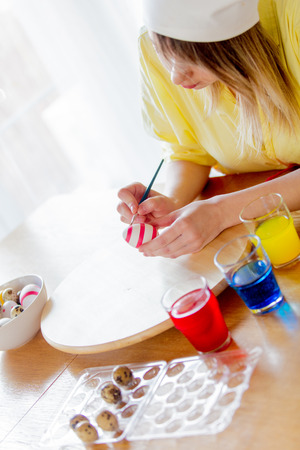 young female as chef painting eggs for Easter Holiday at home.の写真素材