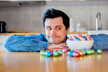 Funny man with Easter eggs on a table at kitchen.