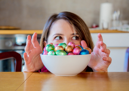 Adult woman and Easter eggs in plate on a wooden table at kitchen in home