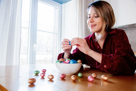 Adult woman and Easter eggs in plate on a wooden table at kitchen in home