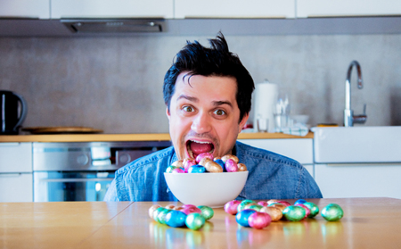 Funny man with Easter eggs on a table at kitchen.