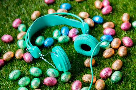 color Chocolate Easter eggs and headphones on green spring grass