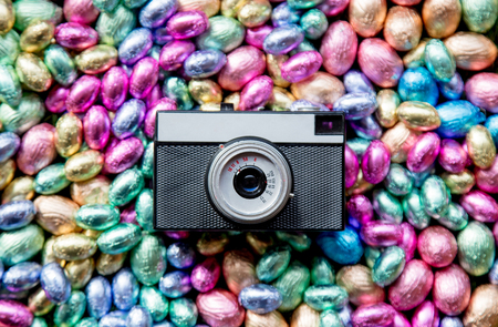 color Chocolate Easter eggs and vintage photo camera on green spring grass
