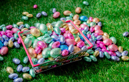 color Chocolate Easter eggs in a meta supermarket basket on green spring grass