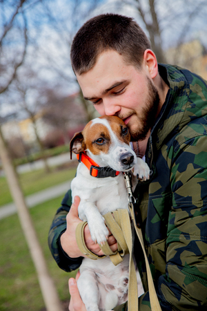 Young man with his dog, Jack Russell Terrier, on the city street in spring time.の写真素材