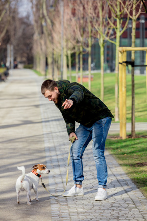 Young man with his dog, Jack Russell Terrier, on the city street in spring time.の写真素材
