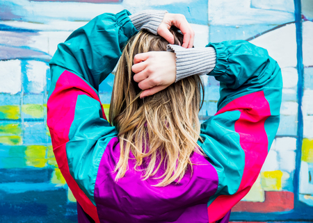 Young woman in jacket of 90s style on colored background
