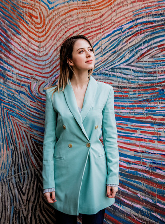 Young woman in Blazer of 90s style stay near striped and colored background.の写真素材