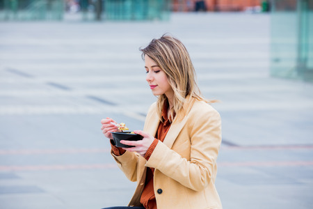 Young businesswoman with salad at urban city outdoor. Coffee break time for a dinnerの写真素材