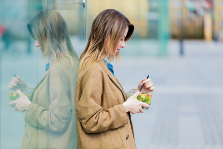 Young businesswoman with salad at urban city outdoor. Coffee break time for a dinnerの写真素材
