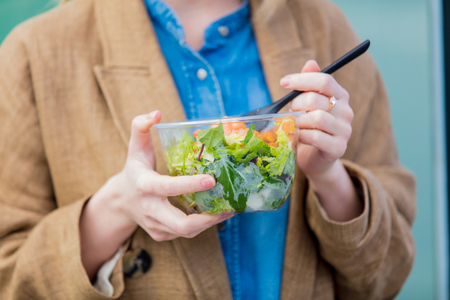 Young businesswoman with salad at urban city outdoor. Coffee break time for a dinnerの写真素材