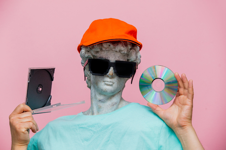 Antique bust of male in cap with sunglasses and CD on pink background. Ready for summer vacation