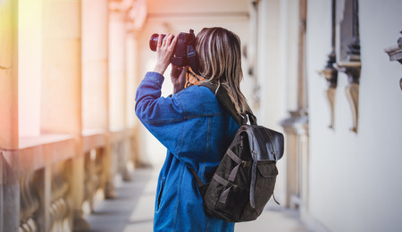 Young woman, professional photographer with camera in old castle. Traveler concept