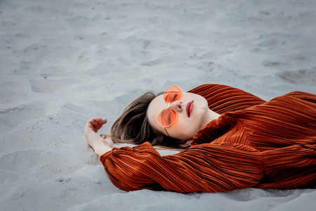 Style adult woman in sunglasses and burgundy color blouse lying down on on a sand, beach. Above ivewの写真素材
