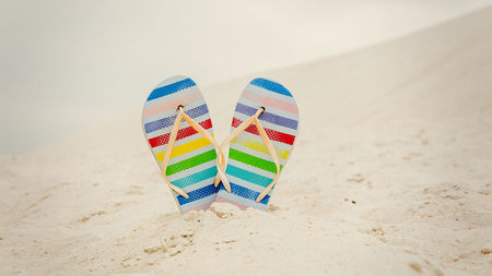 Flip flops shoes in color stripes on a white sand.の写真素材