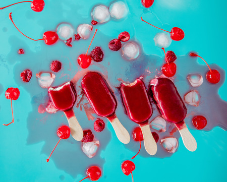 raspberries and cherry ice lolly on blue background. Object without shadowsの写真素材